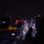 Seoul rooftops at night with a neon-lit street in the distance
