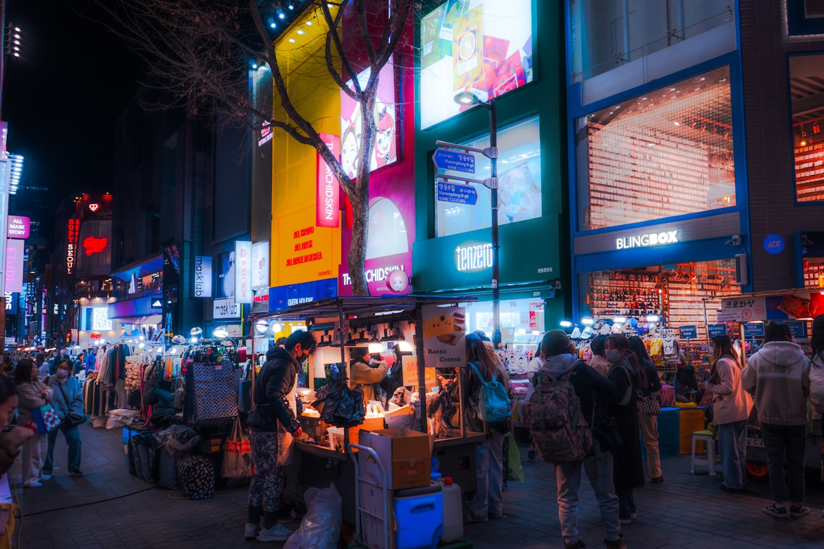 Crowded Seoul shopping street at night with a street food cart