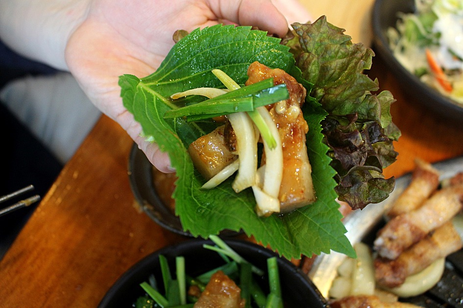 Grilled Korean samgyeopsal wrapped in a perilla leaf with green onion