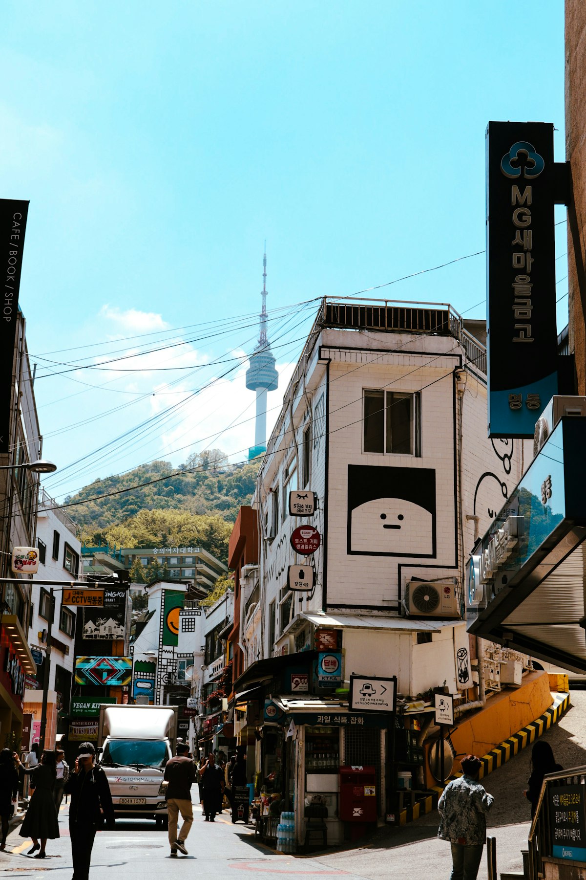 Seoul side street in daylight with N Seoul Tower rising behind the rooftops