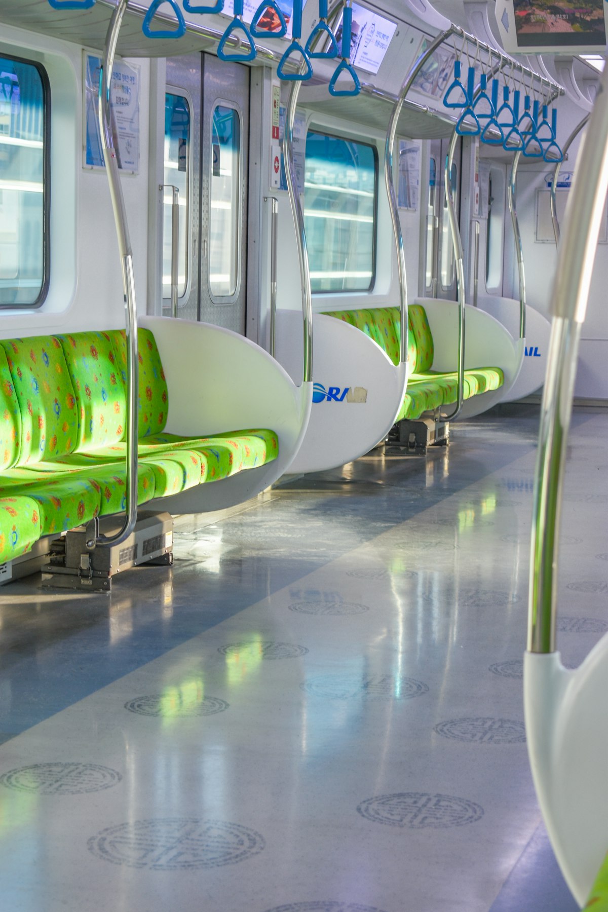 Empty Seoul subway car with green seats and blue hand straps