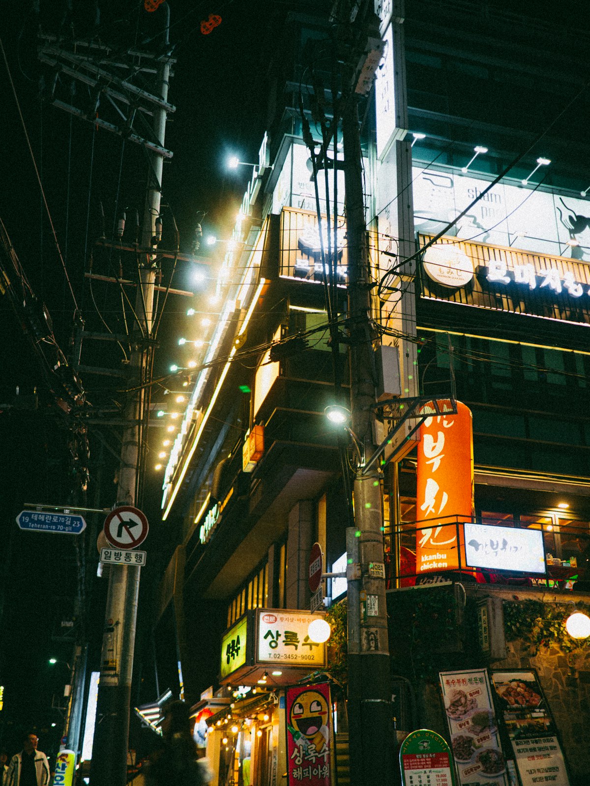 Korean restaurant street at night lined with illuminated signs