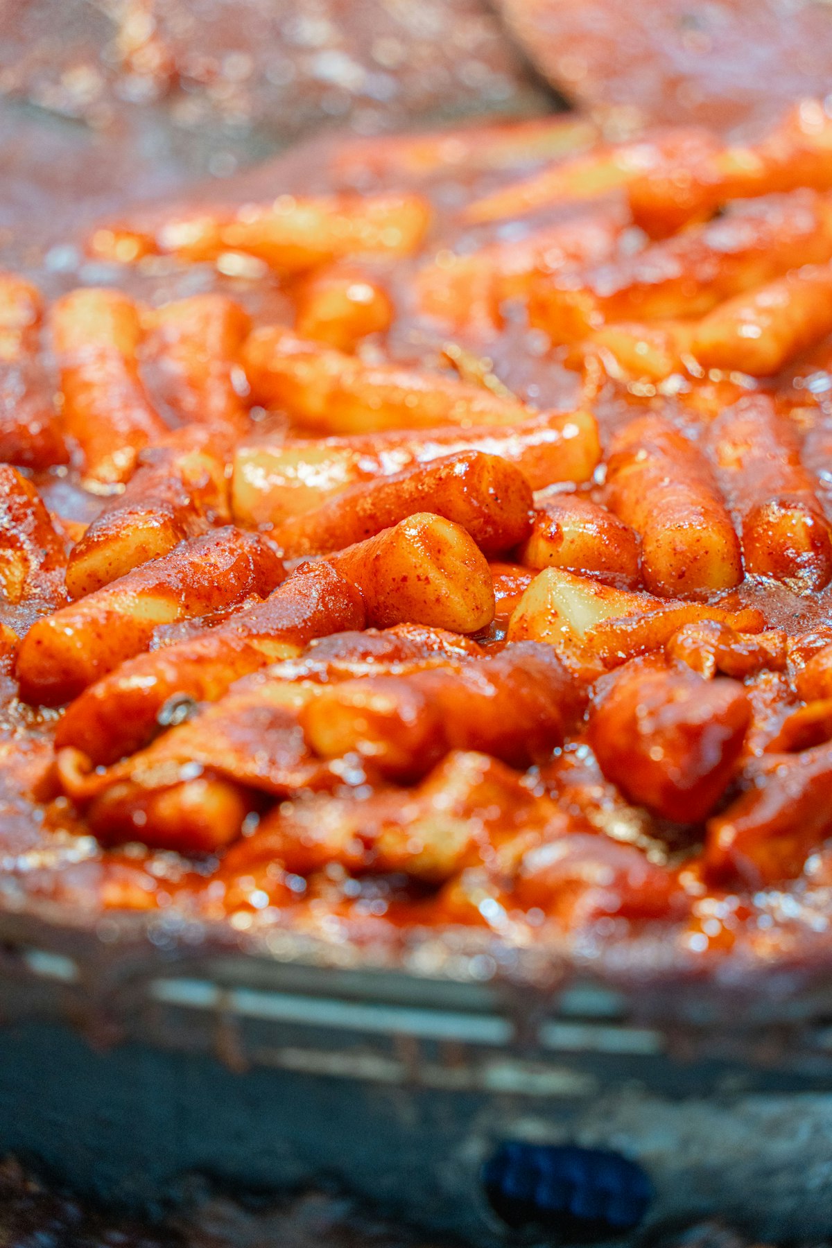 Tteokbokki rice cakes simmering in a wide pan of spicy sauce