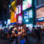 Crowded Seoul shopping street at night with a street food cart